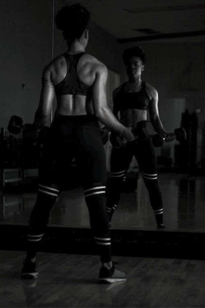 Woman lifting weights looking into mirror